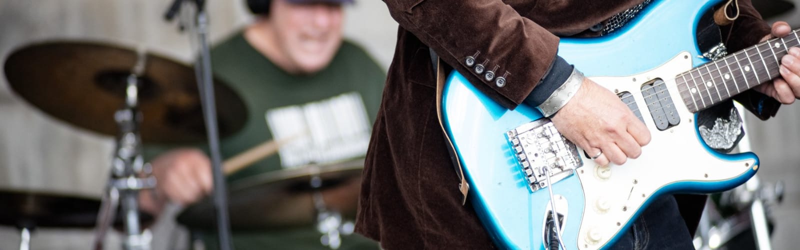 Person playing guitar and drummer in background