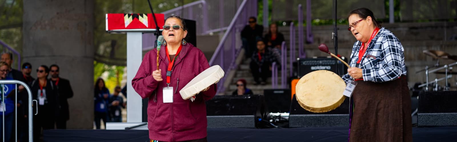 Two Indigenous Women singing and playing the drum